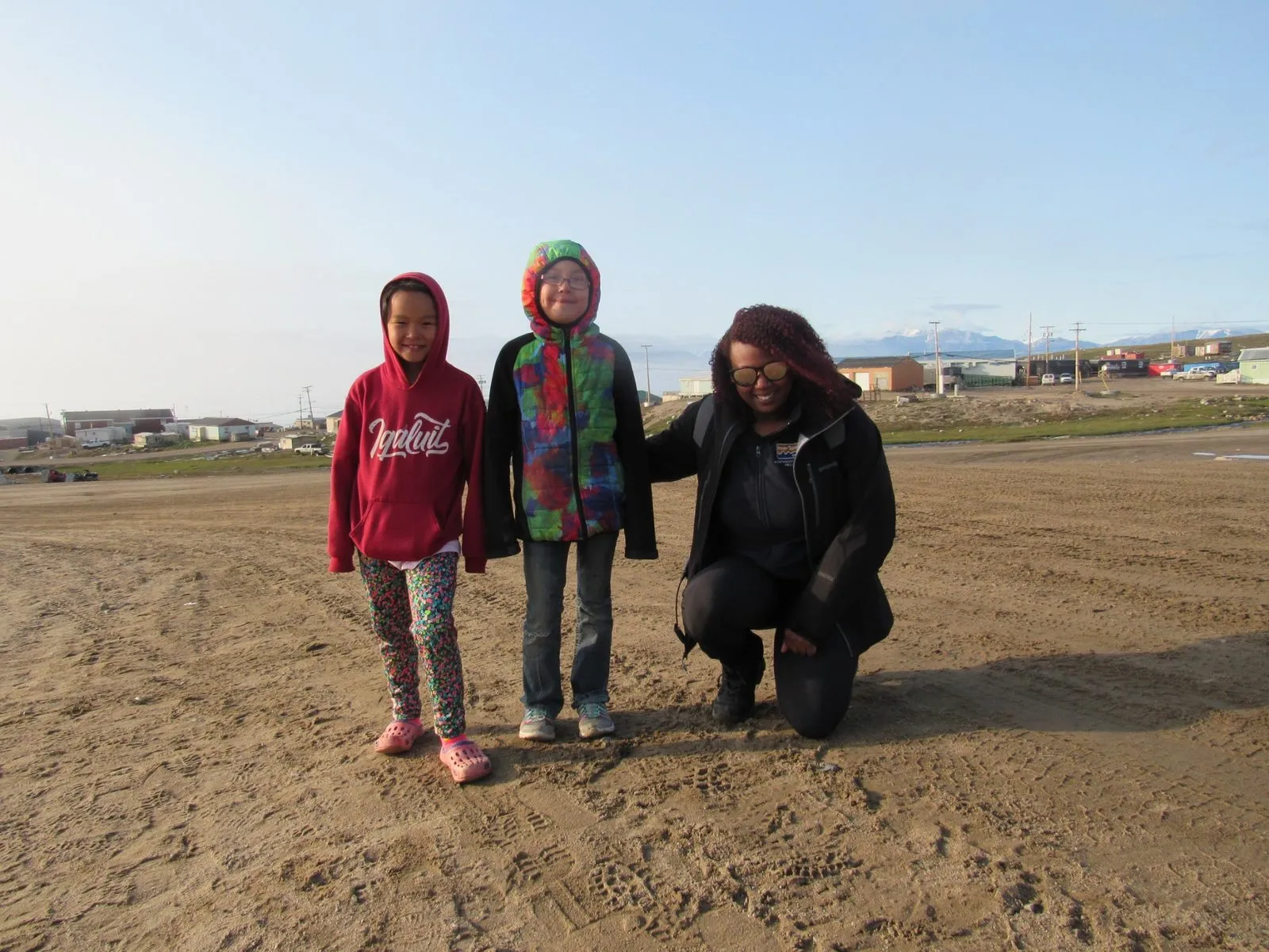 Three people standing together outdoors on open ground