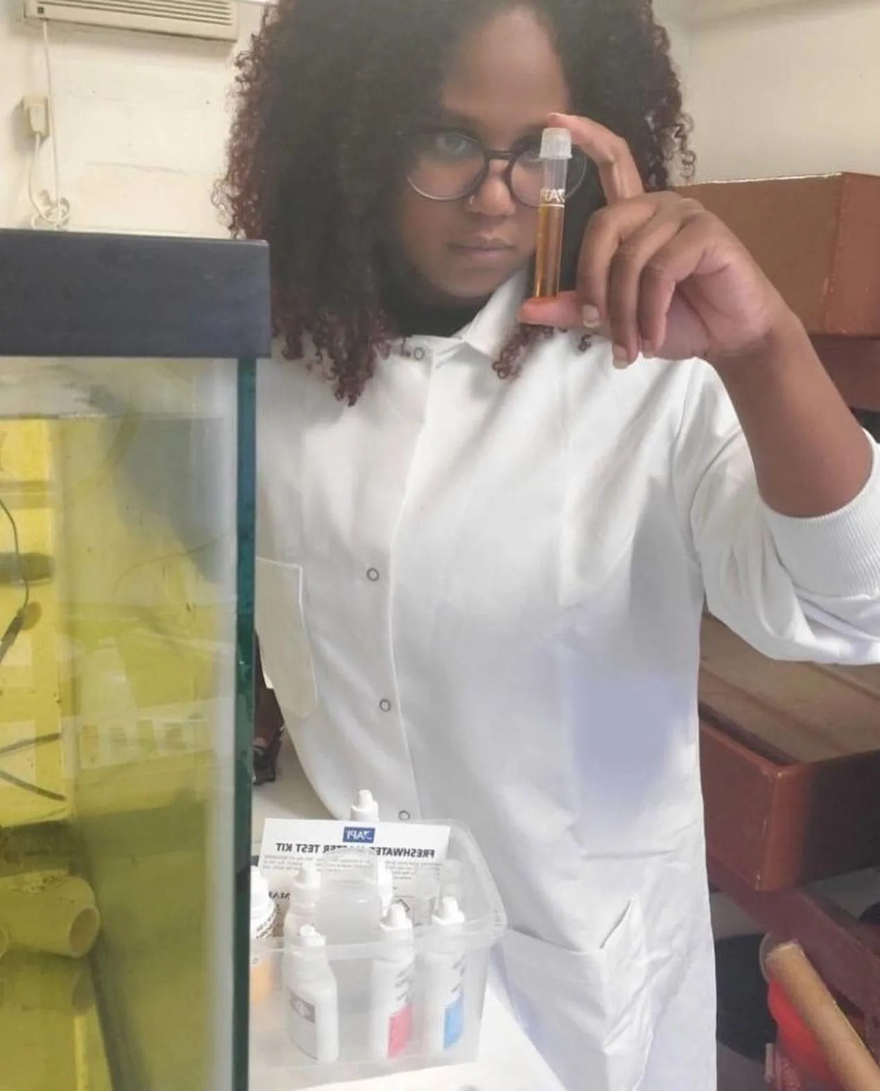 A researcher in a lab coat examining a sample tube