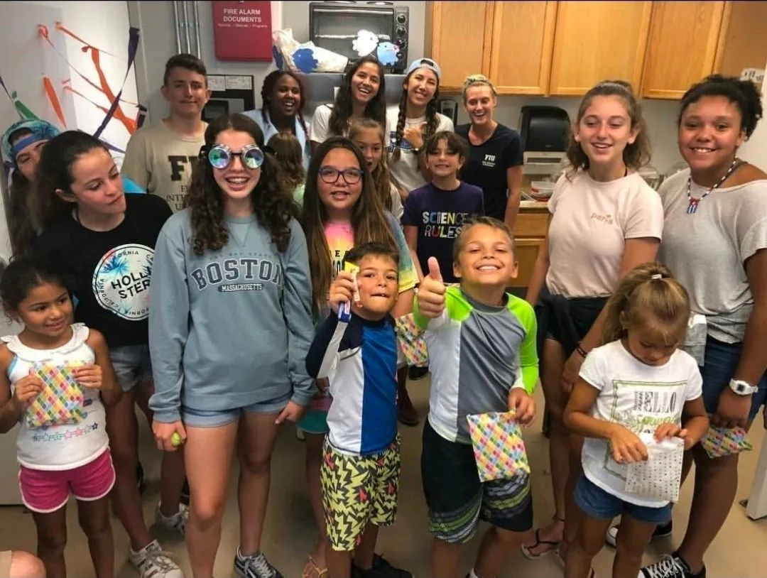 A group of children and adults posing together at an outreach event